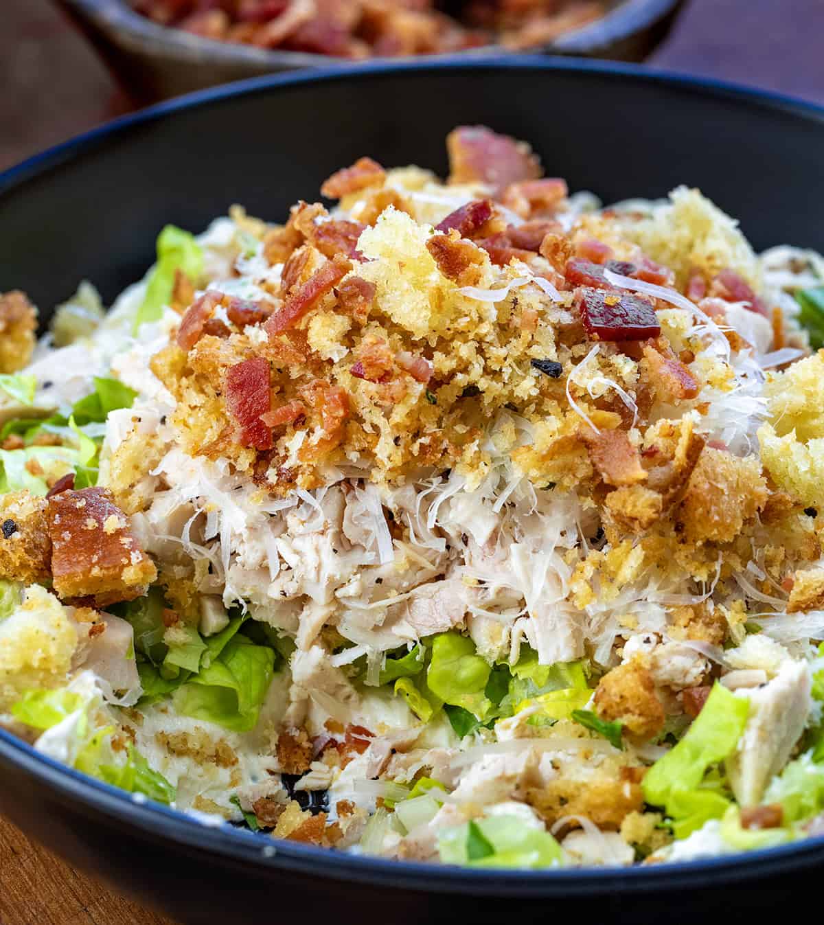 CLose up of a bowl of Chicken Caesar Salad Dip with some of it removed.