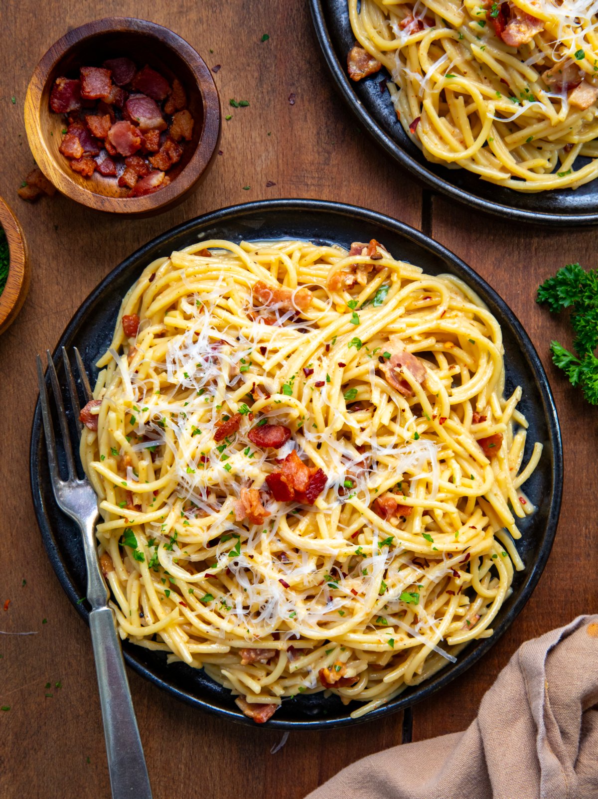 Plates of Chipotle Bacon Carbonara on a wooden table from overhead.