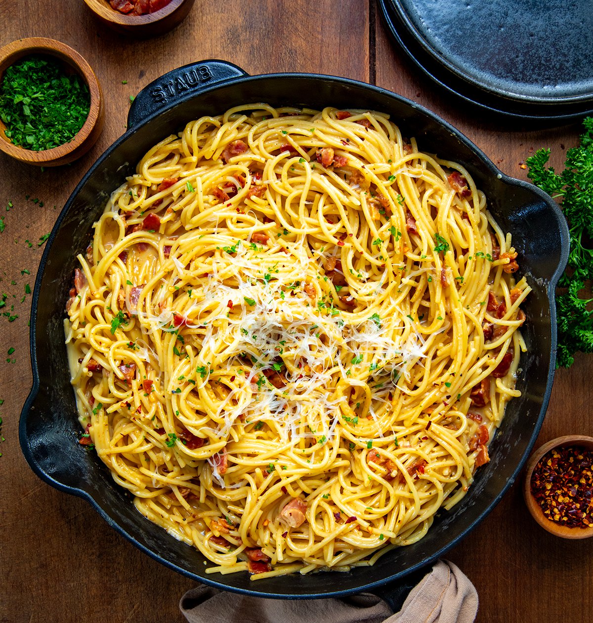 Skillet of Chipotle Bacon Carbonara on a wooden table from overhead.