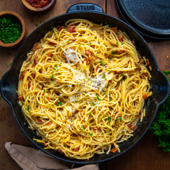 Skillet of Chipotle Bacon Carbonara on a wooden table from overhead.