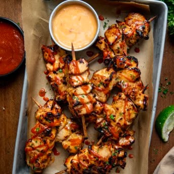 Chipotle Bang Bang Chicken Skewers in a tray on a wooden table from overhead.