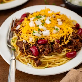 Plate of Cincinnati Chili on a wooden table with a fork on the plate.