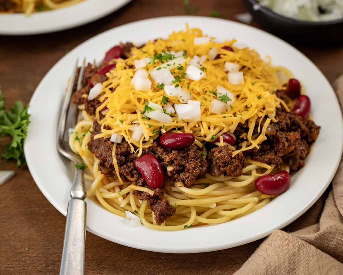 Plate of Cincinnati Chili on a wooden table with a fork on the plate. 