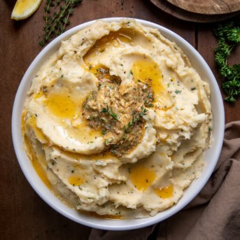 Bowl of Cowboy Butter Mashed Potatoes on a wooden table from overhead.