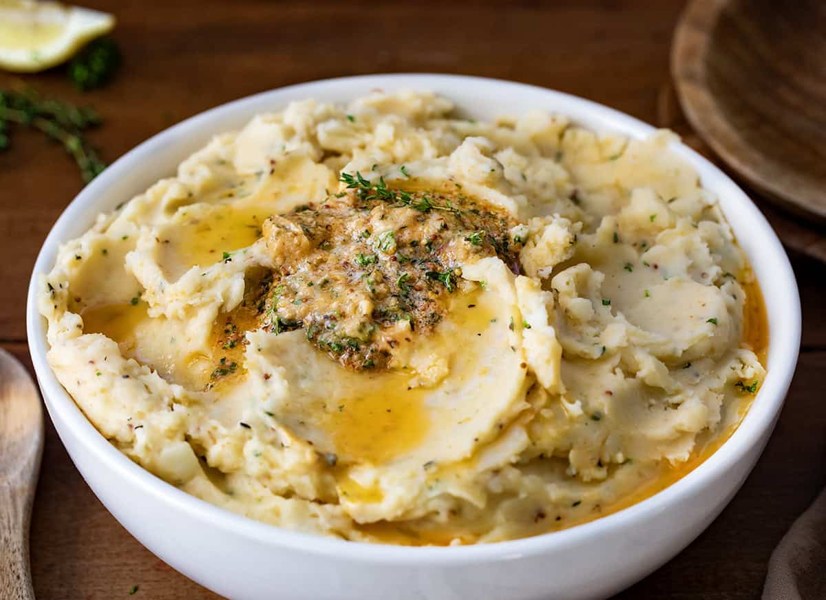 Close up of a Bowl of Cowboy Butter Mashed Potatoes on a wooden table.