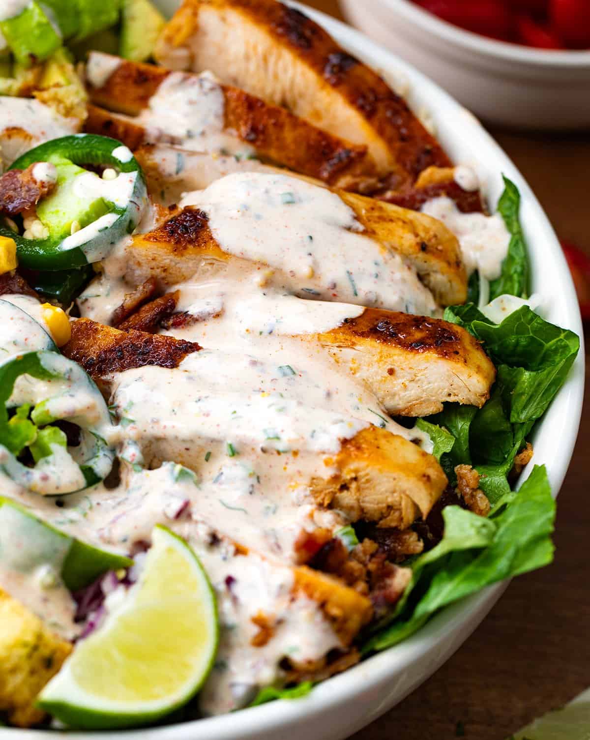 Close up of sliced grilled chicken covered in cowboy ranch dressing.