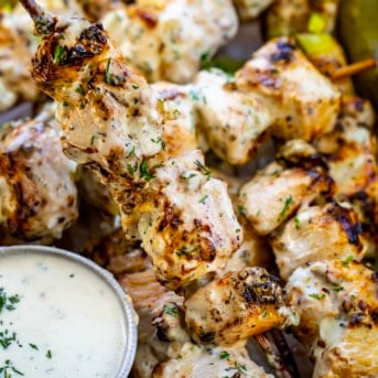 Hand holding a Dill Pickle Ranch Chicken Skewer up from the pan.