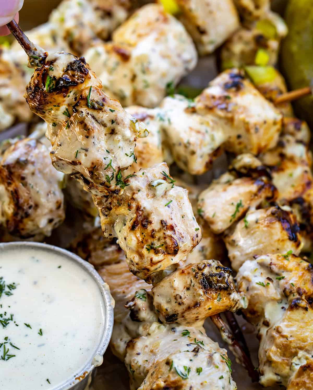 Hand holding a Dill Pickle Ranch Chicken Skewer up from the pan.