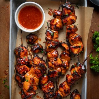 Basket of Firecracker Chicken Skewers on a wooden table from overhead.