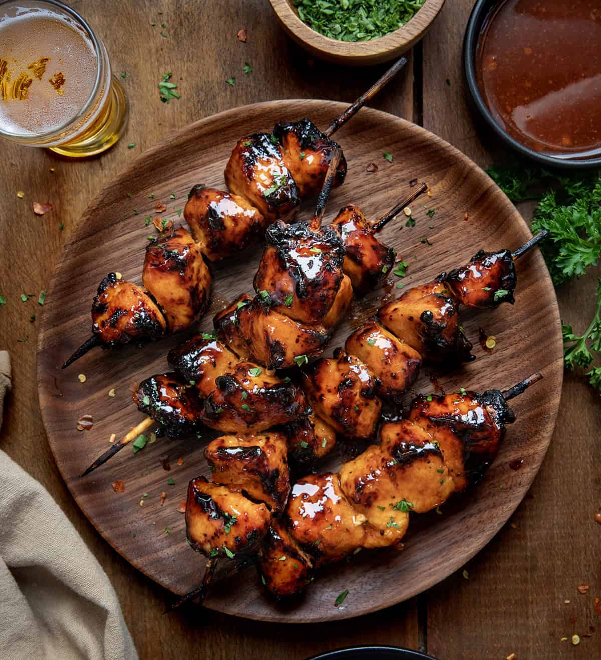 Firecracker Chicken Skewers on a plate on a wooden table from overhead.