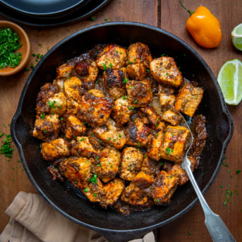 Skillet of Jerk Salmon Bites with a spoon in the skillet from overhead.