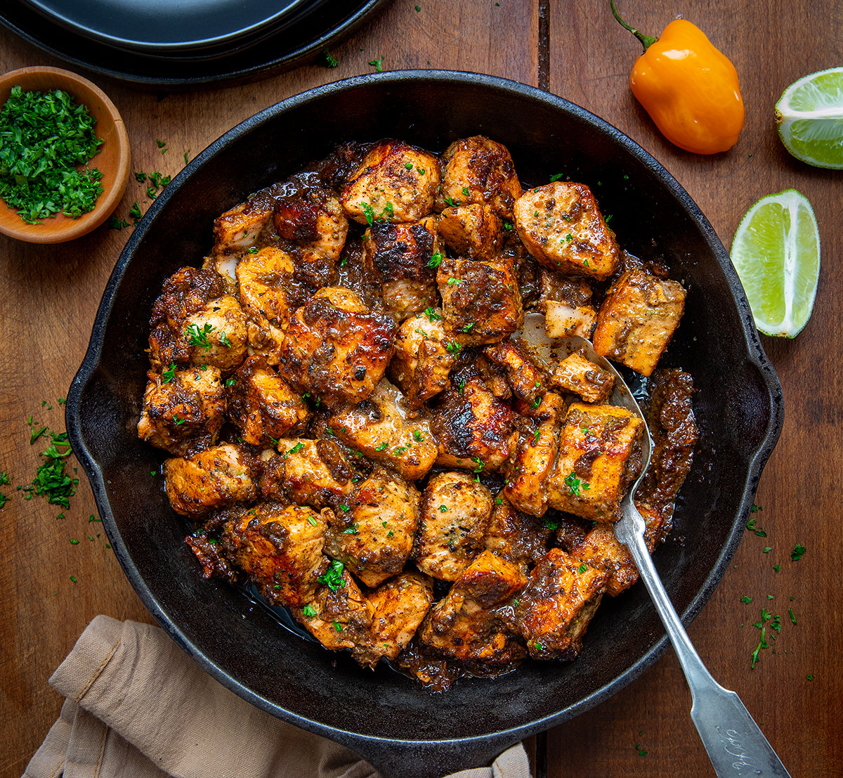 Skillet of Jerk Salmon Bites with a spoon in the skillet from overhead.