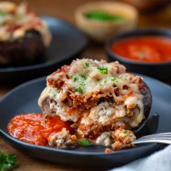 Cit in half Lasagna Stuffed Mushroom on a plate with a fork close up.