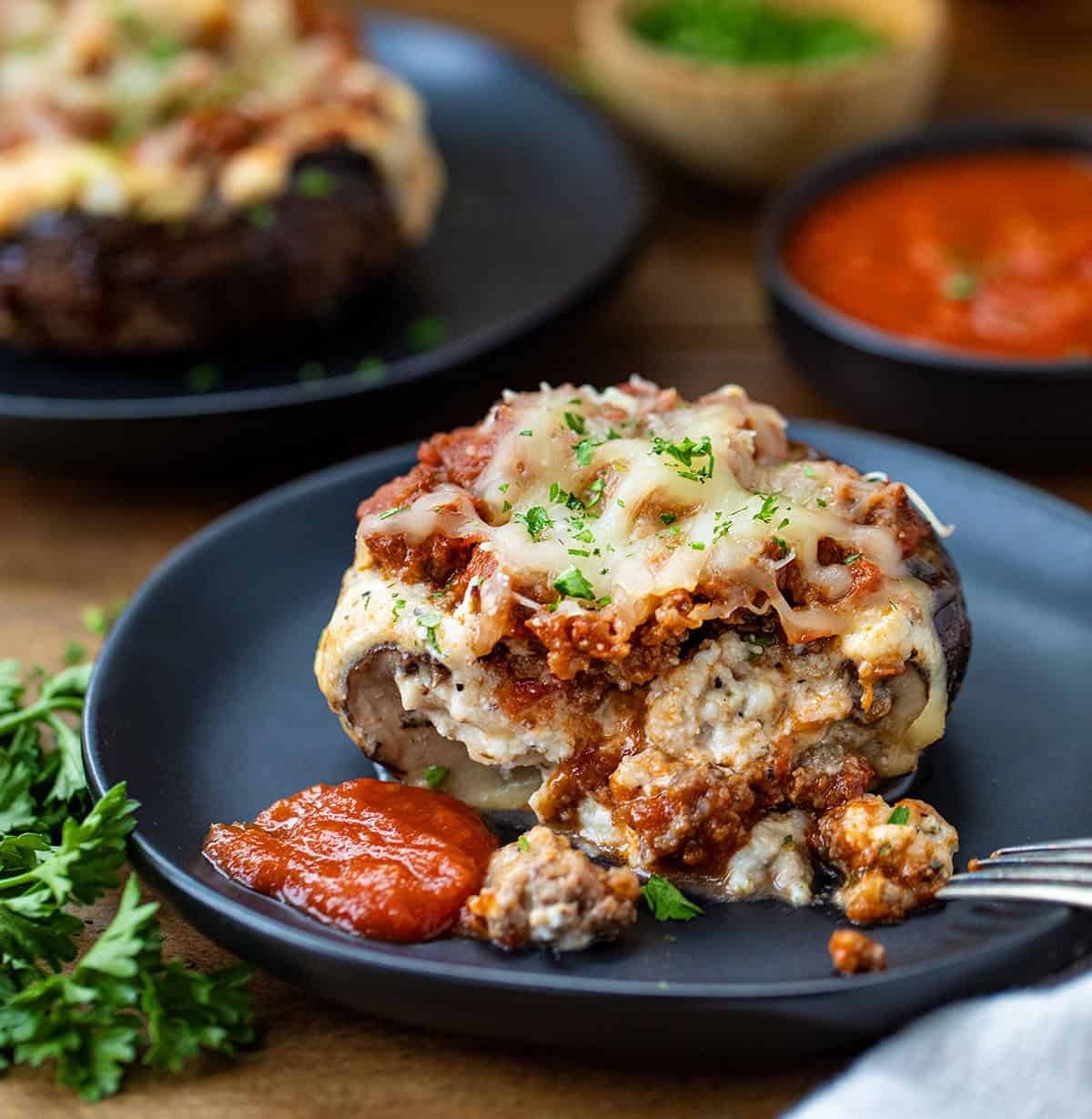 Cut in half Lasagna Stuffed Mushroom on a plate with a fork.