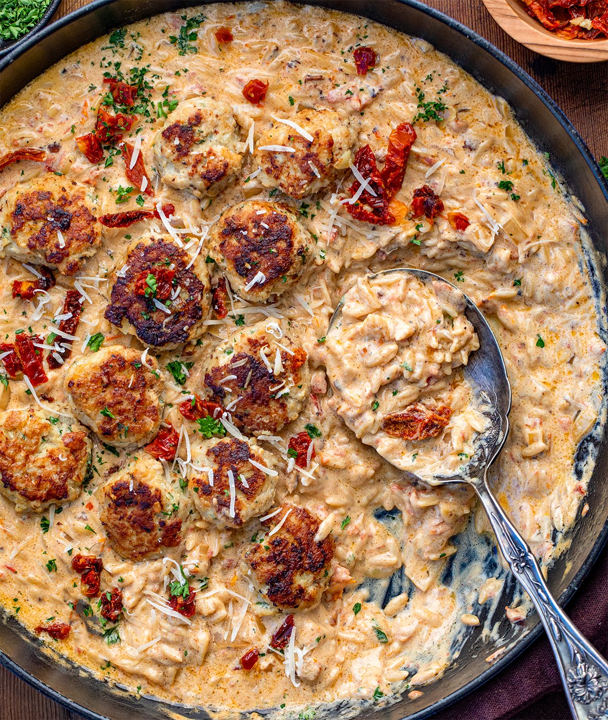 Marry Me Chicken Meatball Orzo with a spoon in the pan showing the creamy orzo.