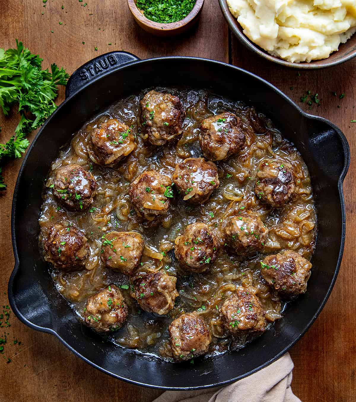 Skillet of Salisbury Steak Meatballs on a wooden table from overhead. 