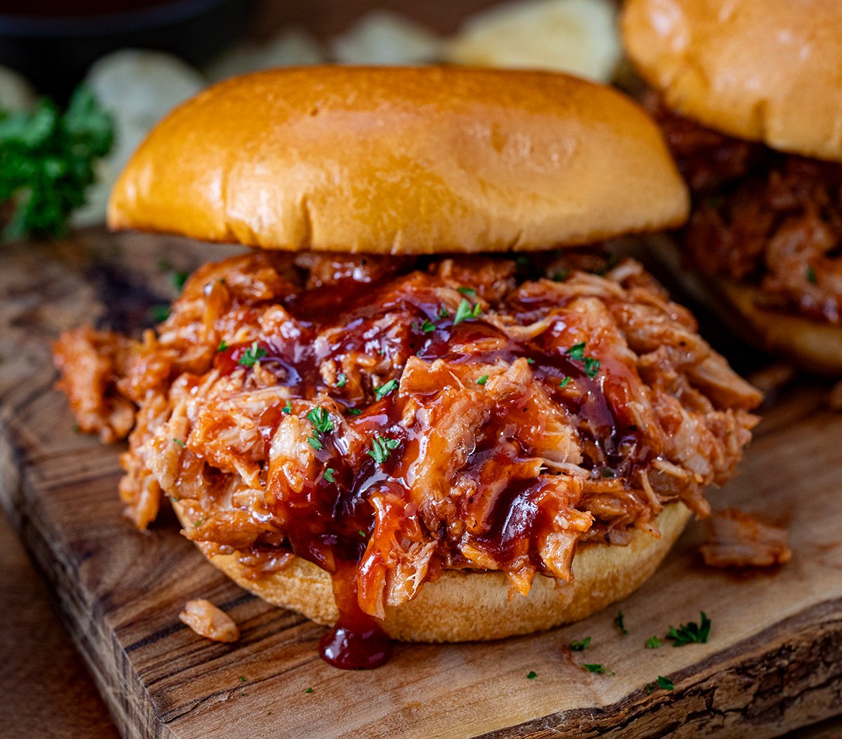 Two Ingredient Pulled Pork on a bun on a wooden table.