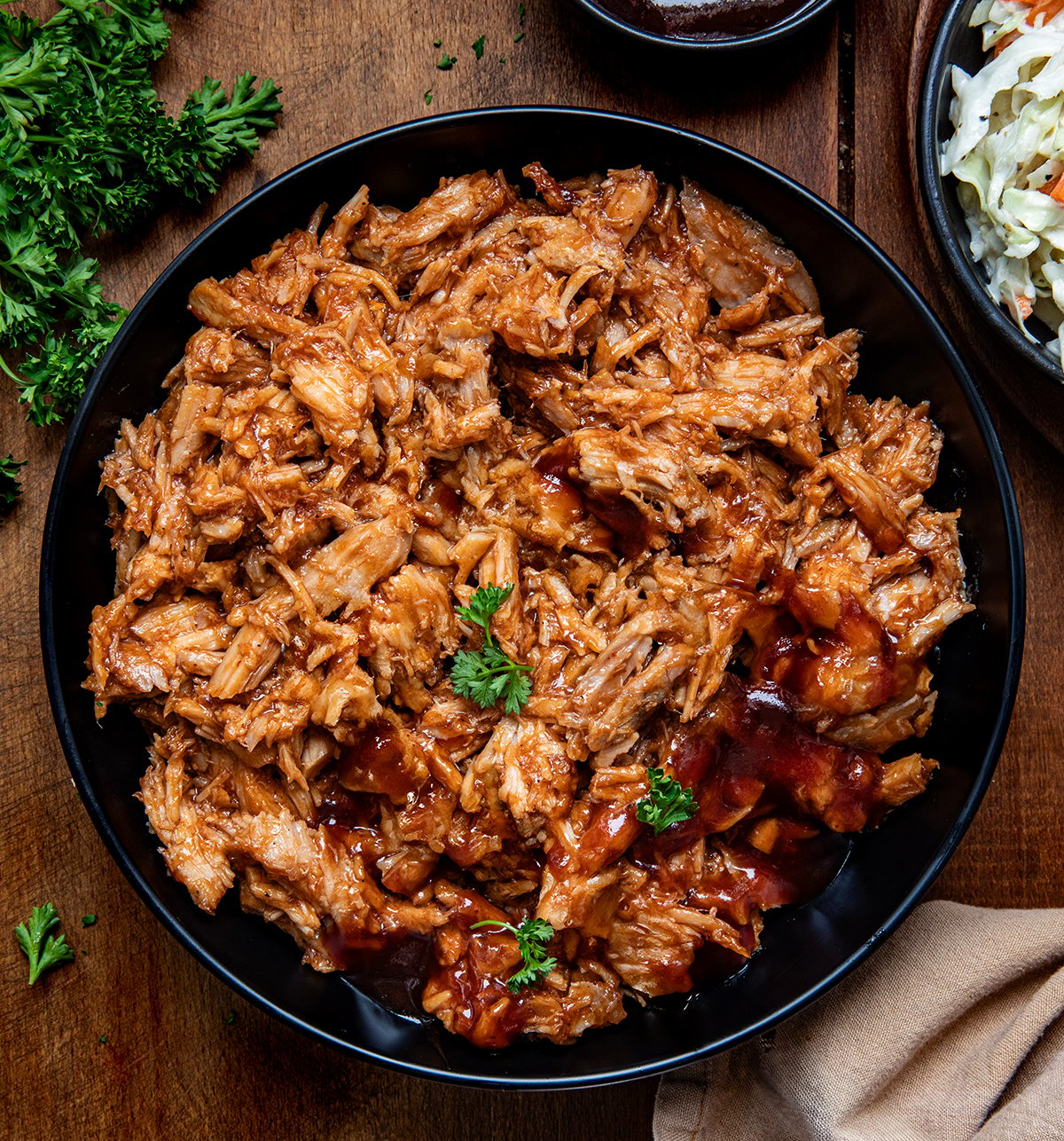 Bowl of Two Ingredient Pulled Pork on a wooden table from overhead.