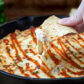 Dipping a chip into cheesy Bang Bang Chicken Dip.