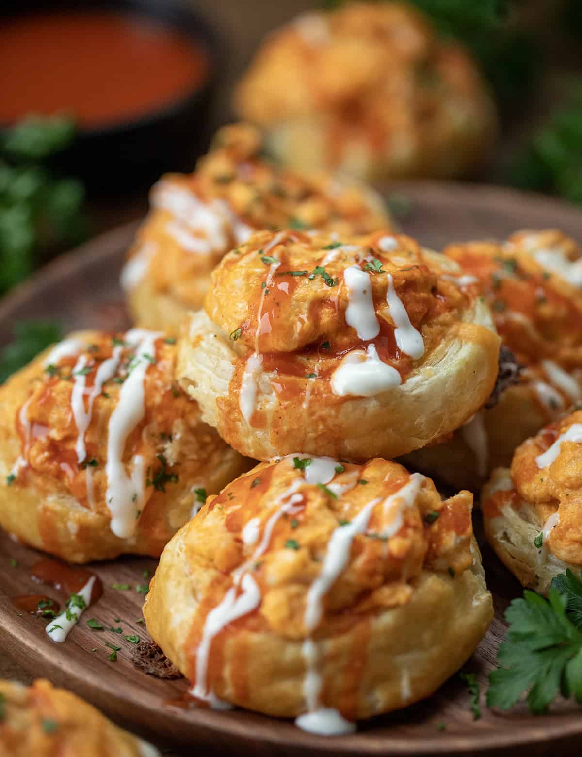 Buffalo Chicken Roll Ups stacked on a plate on a wooden table close up.