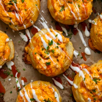 Buffalo Chicken Roll Ups on a piece of parchment paper drizzled with ranch and hot sauce from overhead.