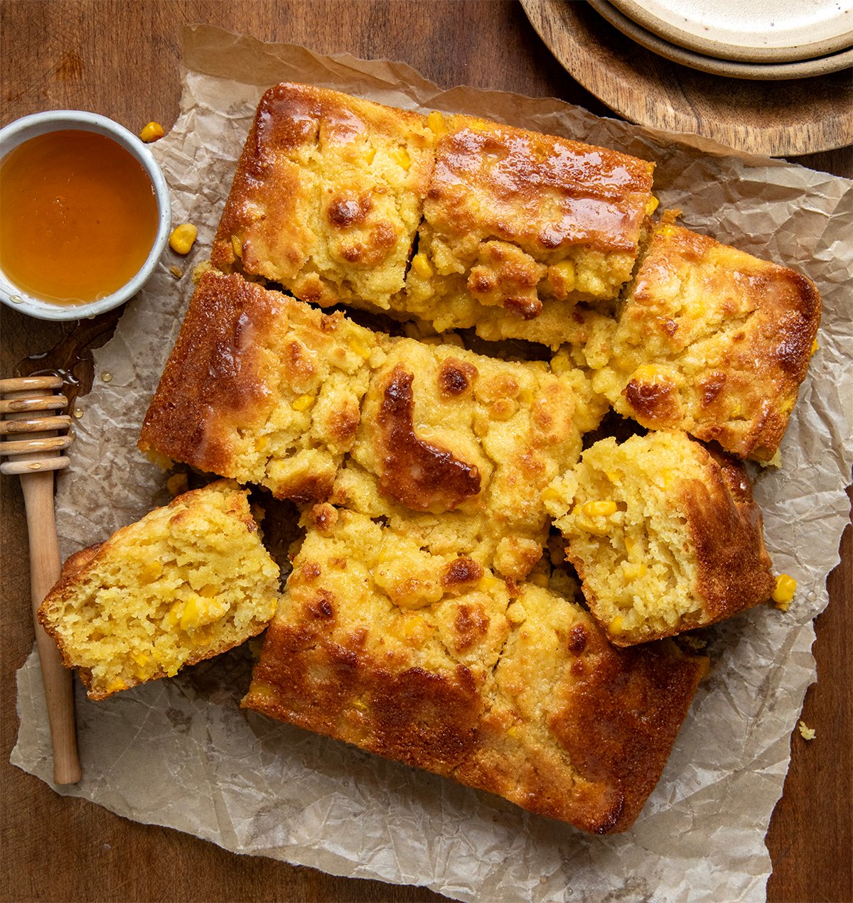 Cornbread Butter Swim Biscuits on a wooden table with honey and plates. 