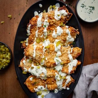 Plate of Dill Pickle Parmesan Chicken on a wooden table from overhead.