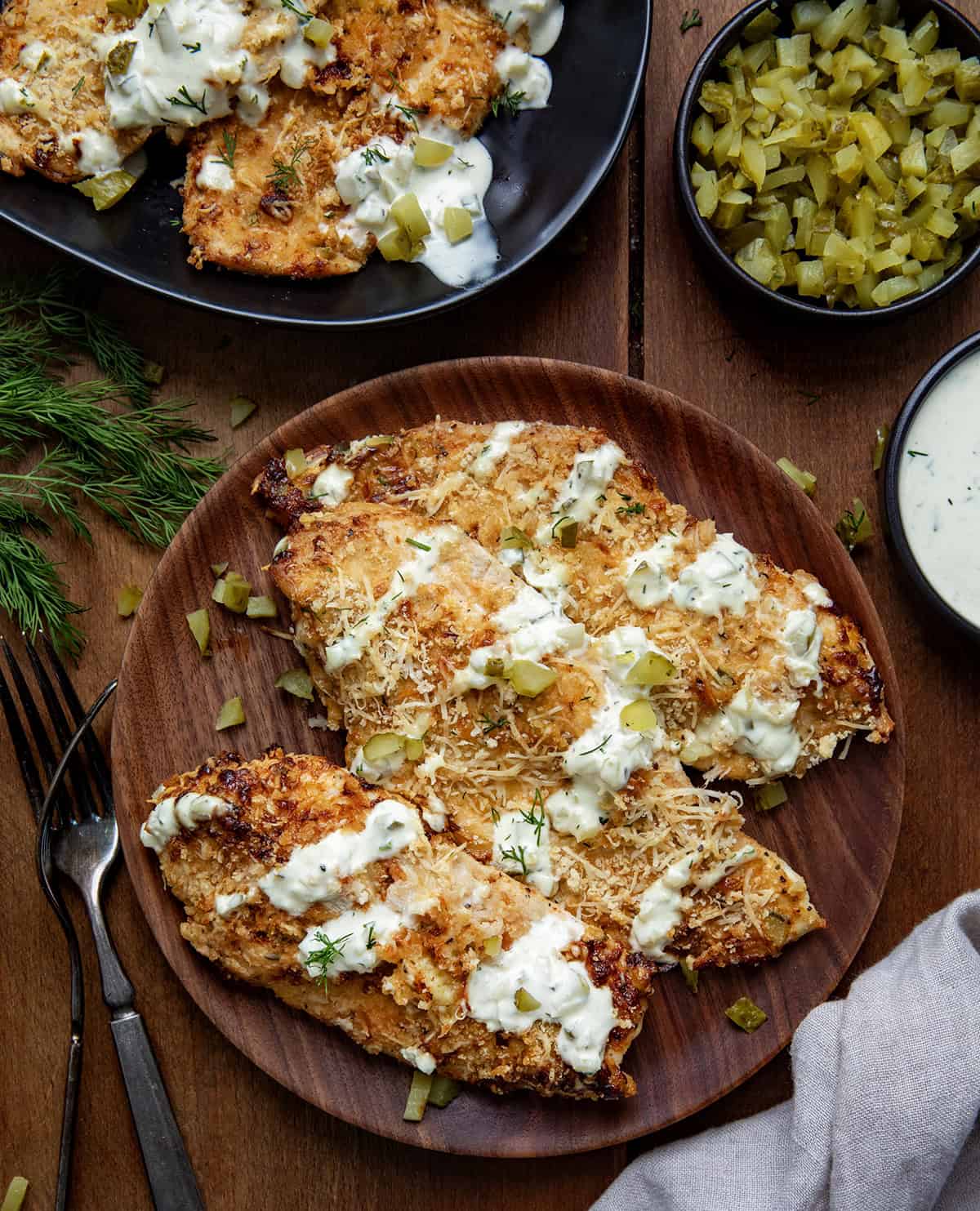 Plate of Dill Pickle Parmesan Chicken on a wooden table from overhead.