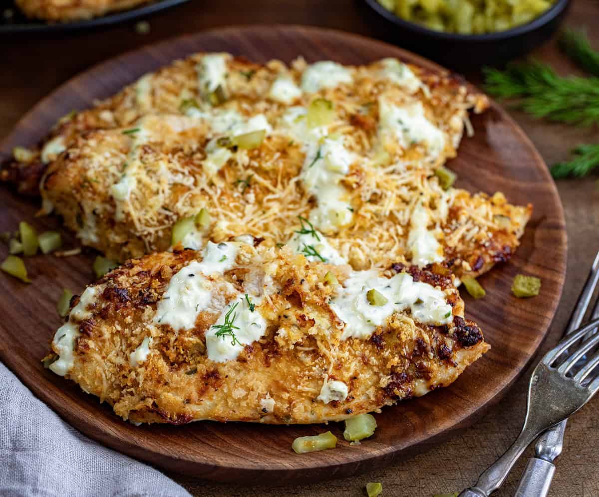 Close up of a plate of Dill Pickle Parmesan Chicken on a woodent table.