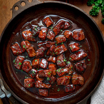 Skillet of Firecracker Steak Bites on a wooden table.