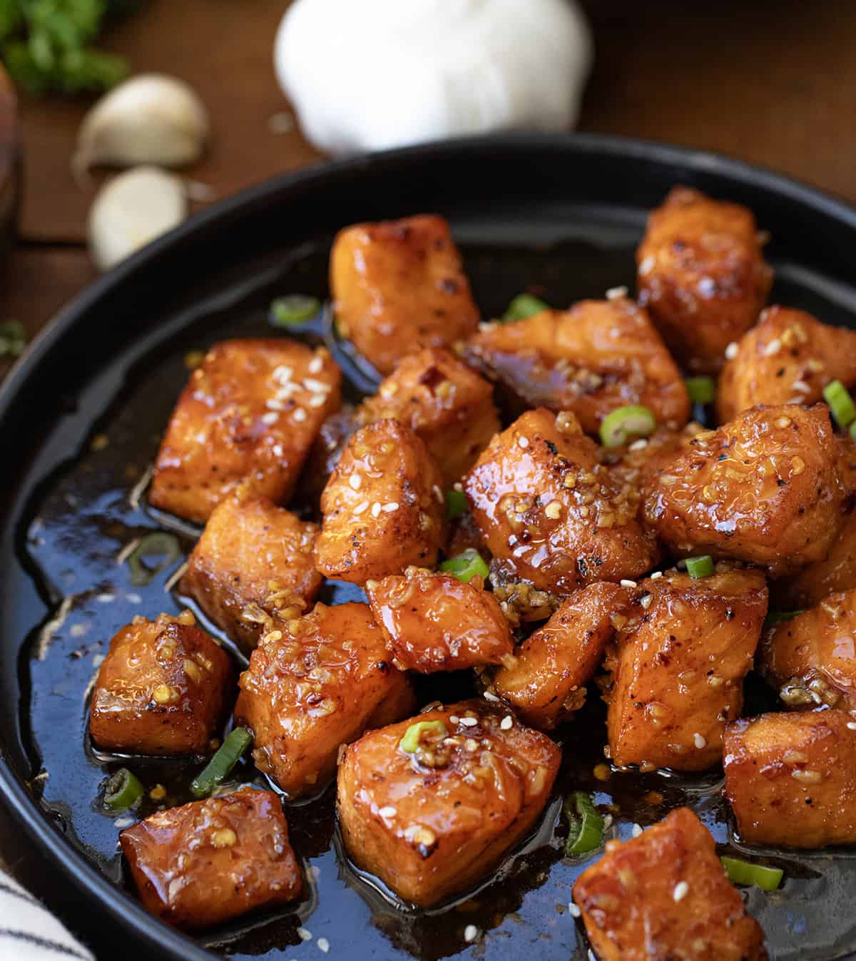 Close up of Honey Garlic Salmon Bites on a black plate.