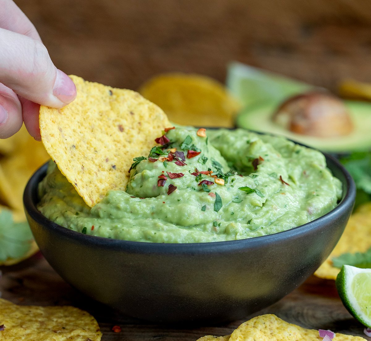 Dipping a chip into Spicy Avocado Dip.