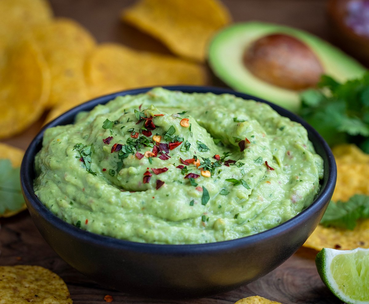 Black bowl of Spicy Avocado Dip on a wooden table.