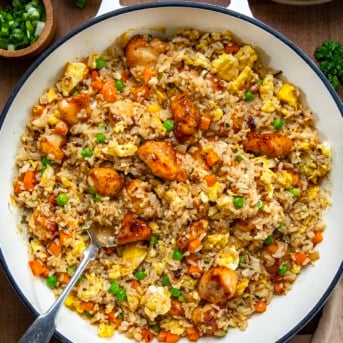 Skillet of Bang Bang Chicken Fried Rice on a wooden table from overhead.