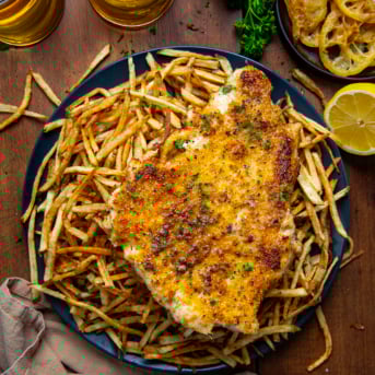 Plate of Chicken With A Thousand Fries on a wooden table from overhead.