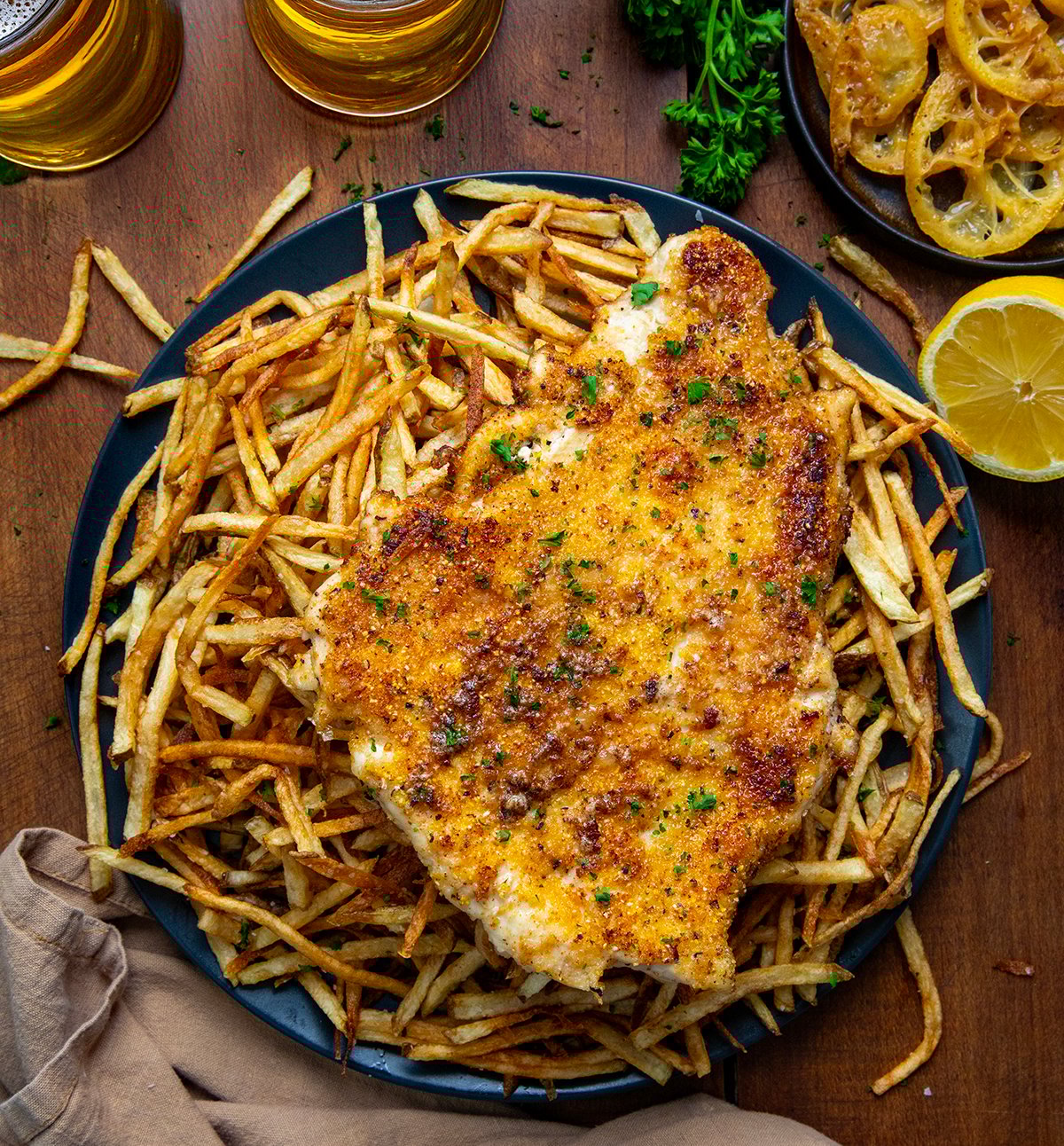 Plate of Chicken With A Thousand Fries on a wooden table from overhead.