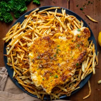Plate of Chicken With A Thousand Fries on a wooden table from overhead.