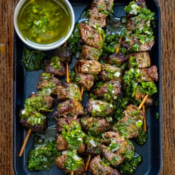 Pan of Chimichurri Steak Skewers on a wooden table from overhead.