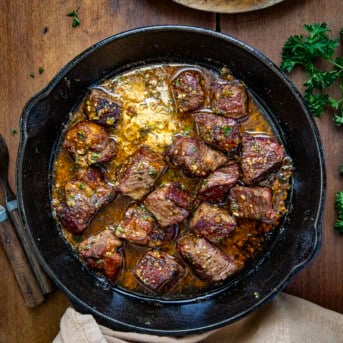 Cowboy Butter Steak Bites in a skillet on a wooden table from overhead.