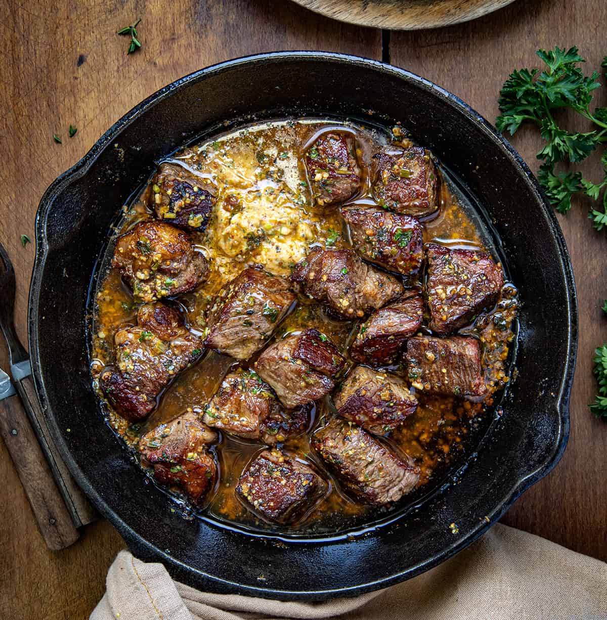 Cowboy Butter Steak Bites in a skillet on a wooden table from overhead.