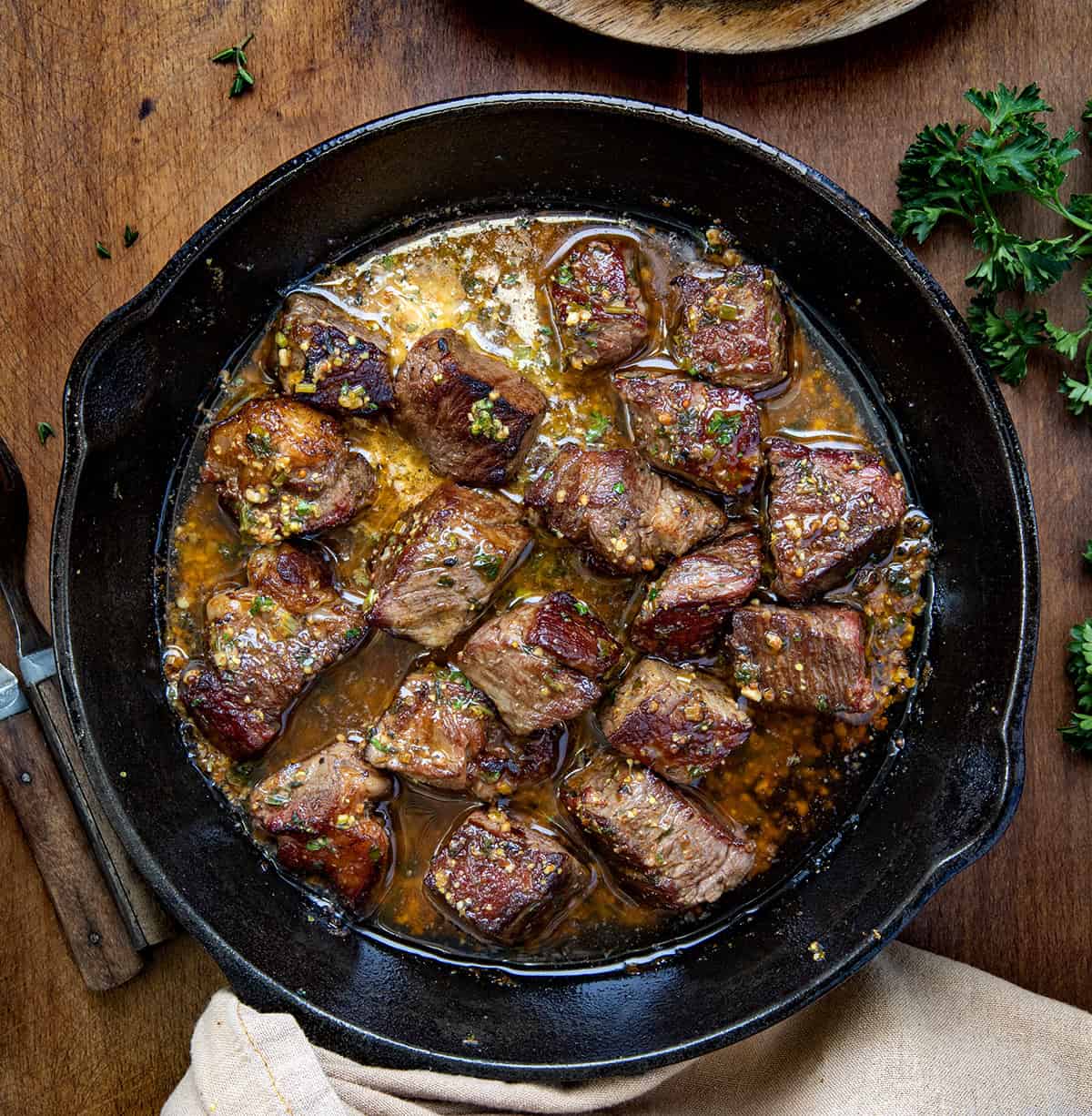 Savor the delicious Cowboy Butter Steak Bites, perfectly cooked bites coated in rich cowboy butter! Quick, easy, and the most delicious! Skillet of Cowboy Butter Steak Bites on a wooden table from overhead.