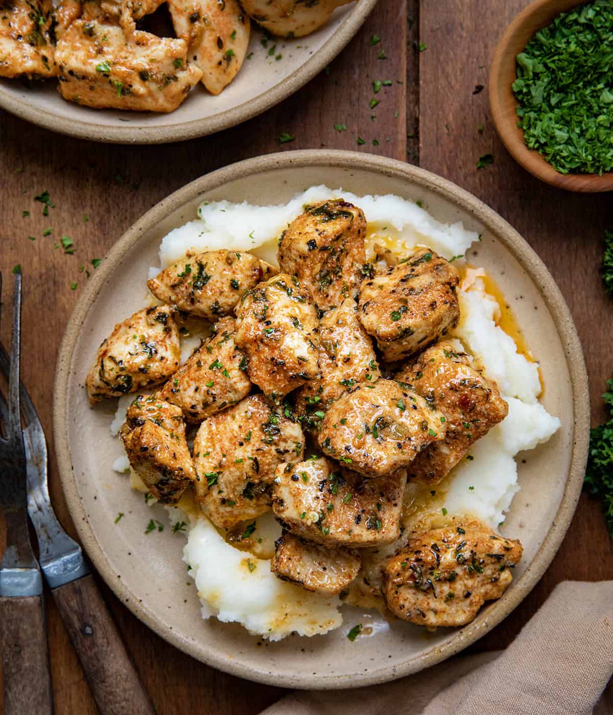 Plates of Cowboy Chicken Bites on mashed potatoes on a wooden table from overhead.