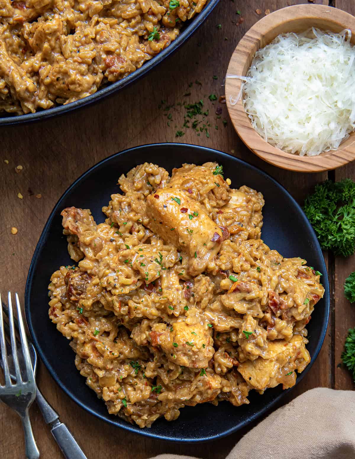 Black plates with Marry Me Chicken and Rice on it on a wooden table form overhead.