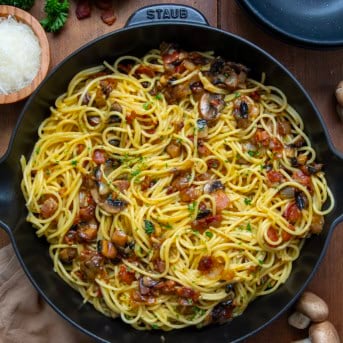 Skillet of Mushroom and Onion Carbonara on a wooden table from overhead.