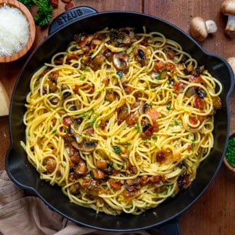 Skillet of Mushroom and Onion Carbonara on a wooden table from overhead.