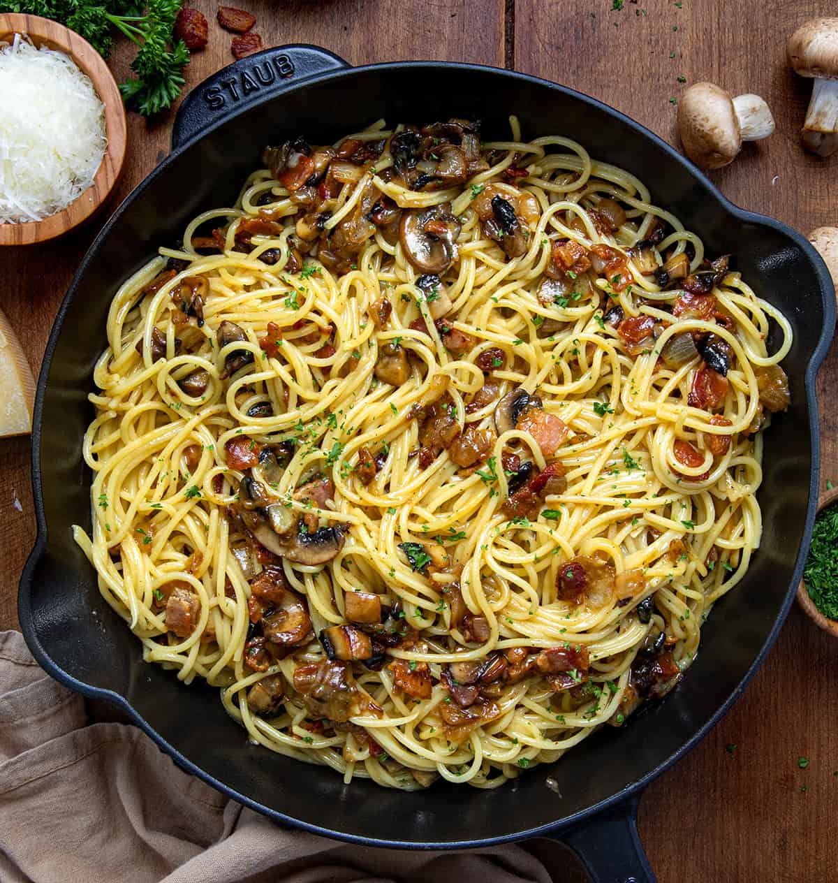 Skillet of Mushroom and Onion Carbonara on a wooden table from overhead.