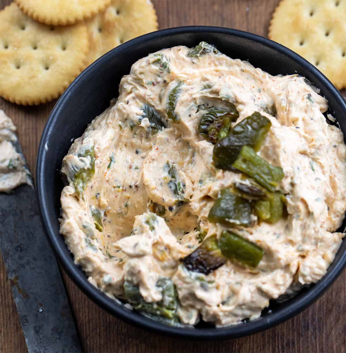 Black bowl with Roasted Jalapeño Cowboy Cream Cheese in it and some has been scooped out.