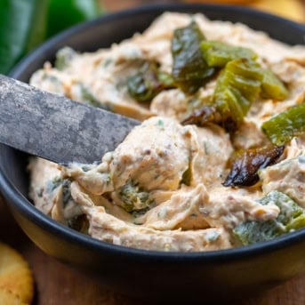 Dipping a knife into Roasted Jalapeño Cowboy Cream Cheese to scoop some out.