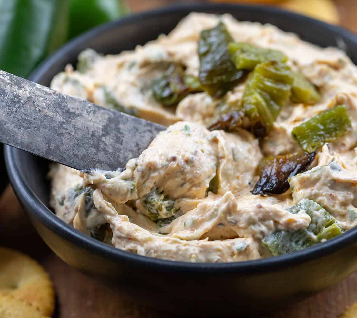 Dipping a knife into Roasted Jalapeño Cowboy Cream Cheese to scoop some out.