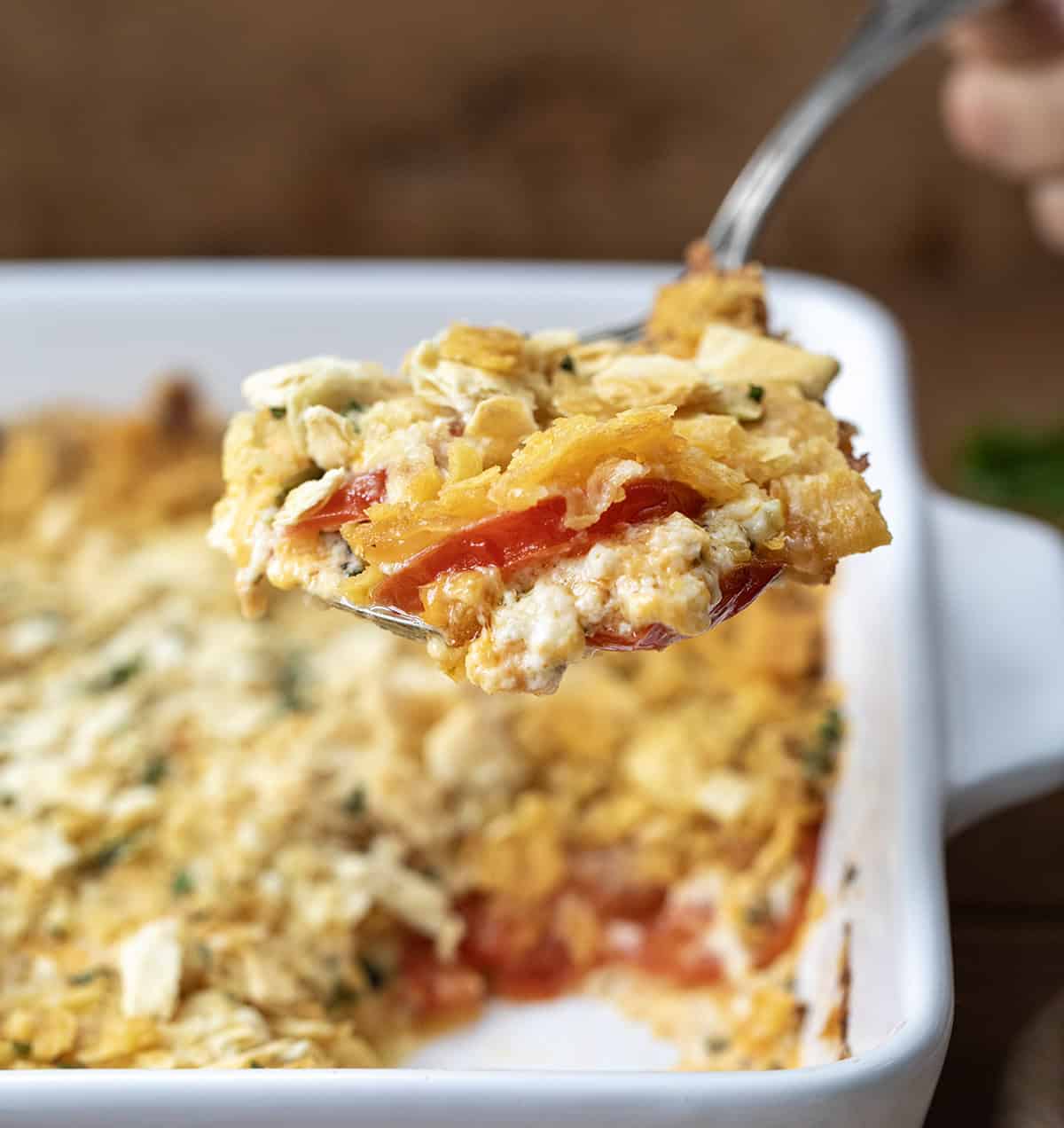 Spoonful of Scalloped Tomatoes held above the dish.